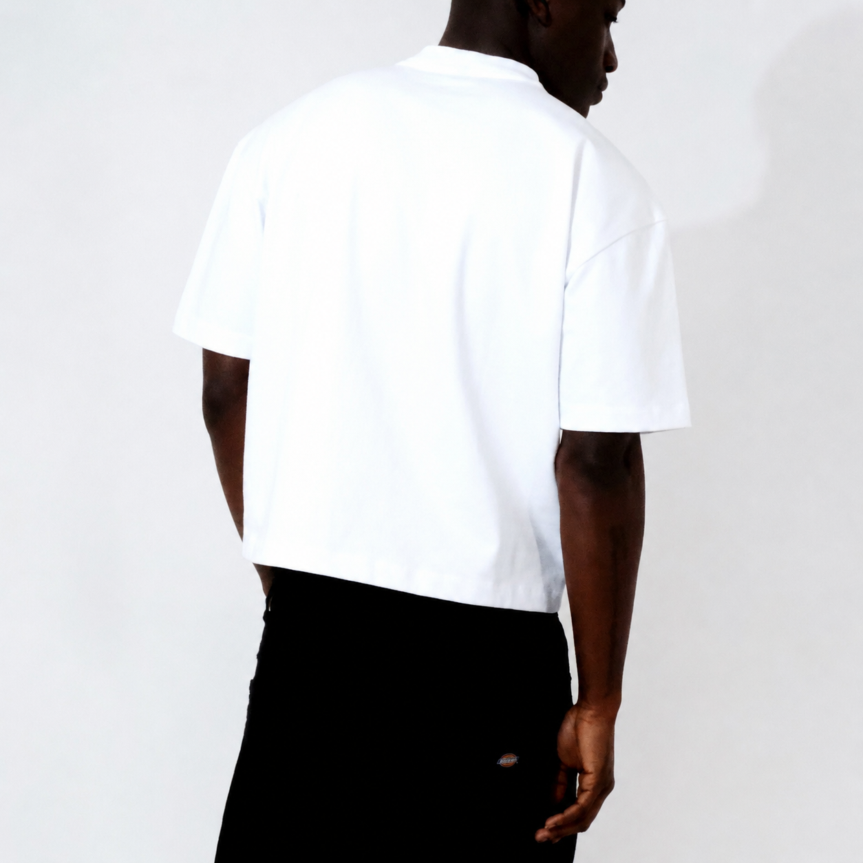 Person wearing a white t-shirt and black pants on a plain background