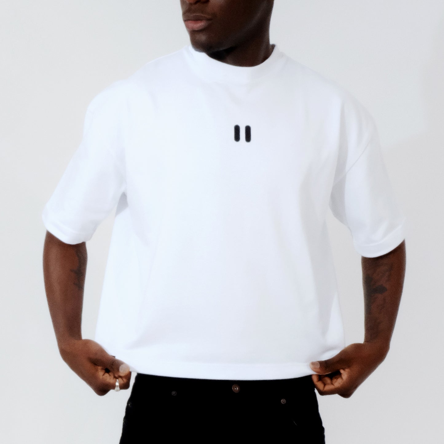Person wearing a white t-shirt with the black roph logo on a plain background